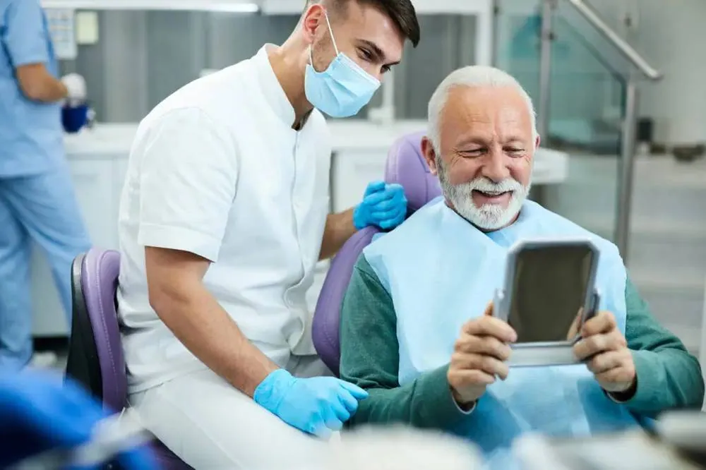 Dentist showing an older patient the result in a hand mirror